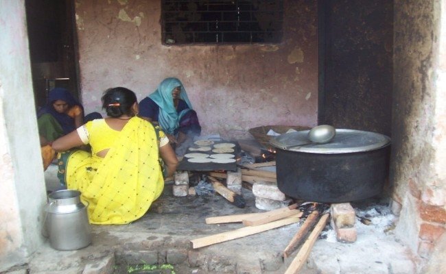 गैस सिलेंडर के भाव बढ़ने से परेशान समूह लकड़ी पर बना रहे भोजन